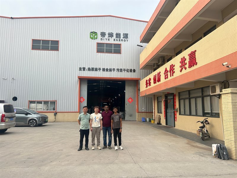 Four visitors posing in the courtyard in front of the Diye Energy plant buildings in Foshan