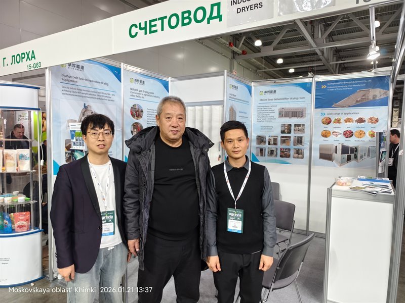 Three staff posing in front of the Diye Energy drying-equipment panels at a trade fair