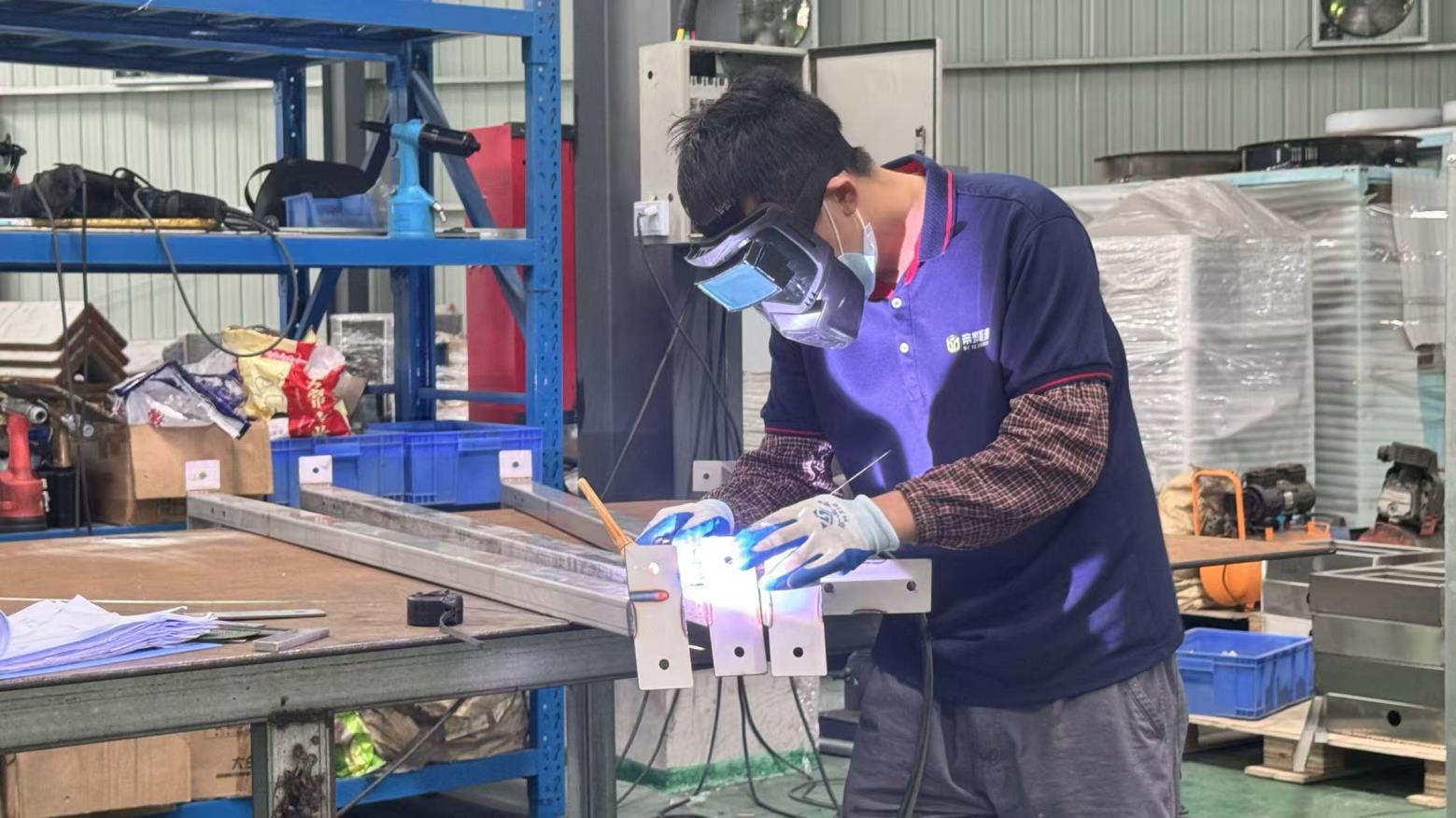 Worker welding a stainless-steel heat pump dryer frame