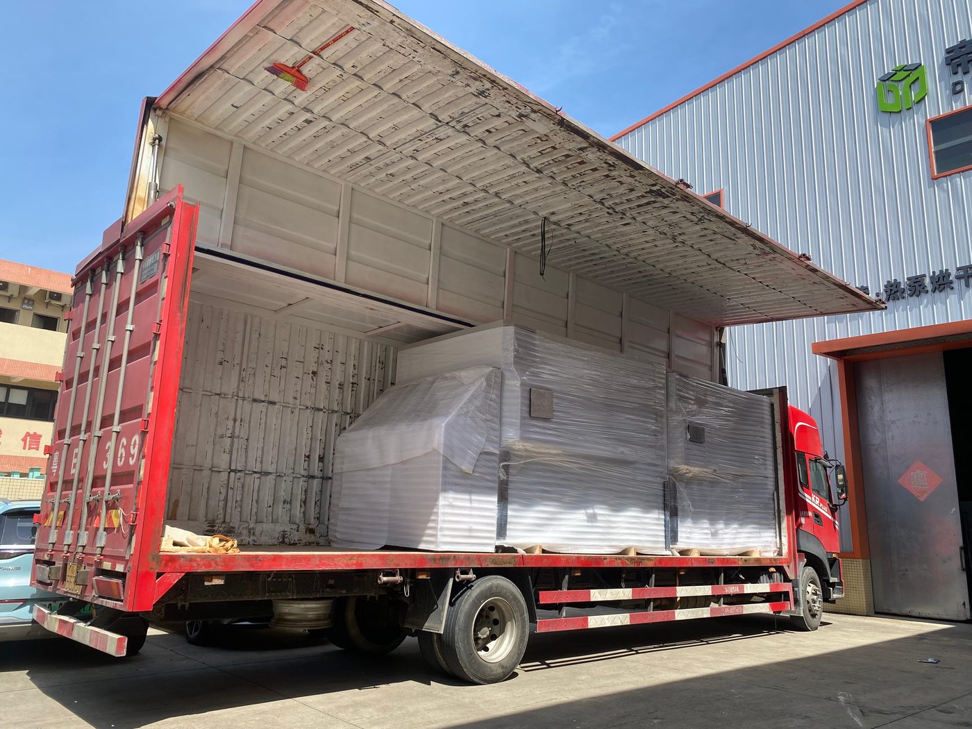 Wing-body trailer opened at the loading dock with a foam-wrapped unit on the forks